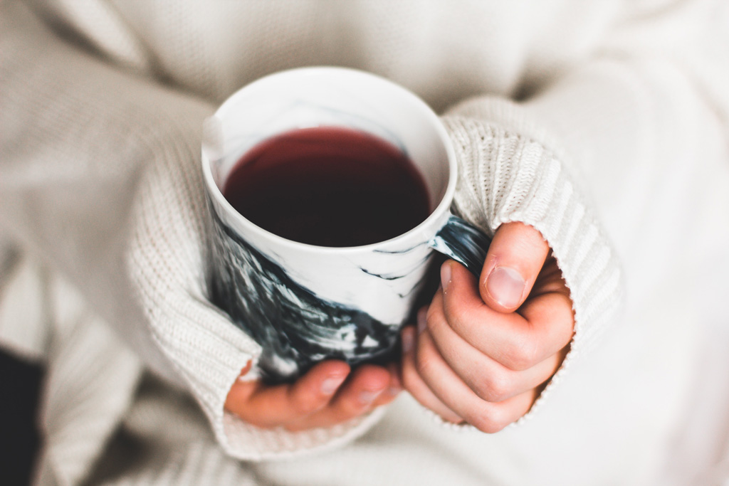 Warming hands on cup of tea in cosy clothes